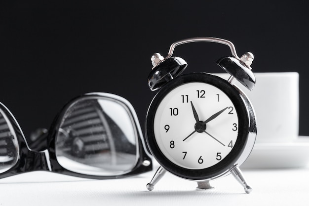 Still life , vintage alarm clock and coffee cup on white table