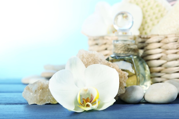 Still life with beautiful blooming orchid flower spa treatment on wooden table on bright background