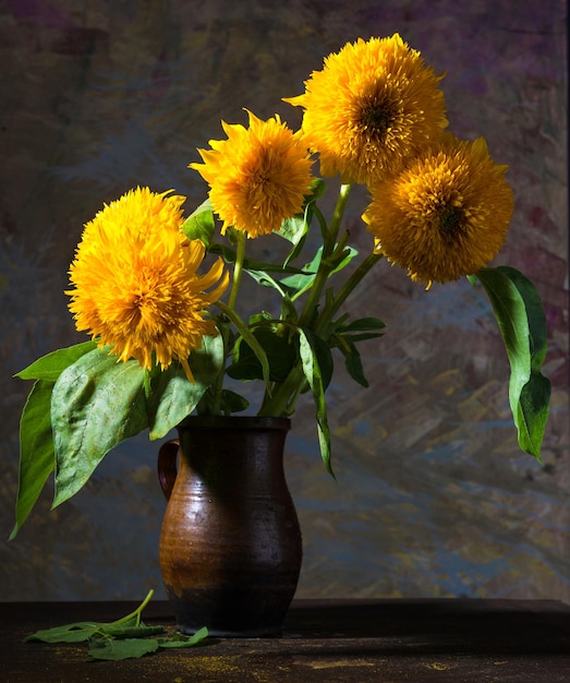 Still life with beautiful sunflowers in vase on a dark background