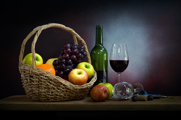 Still life with bottle and glass of red wine, apples and grapes.