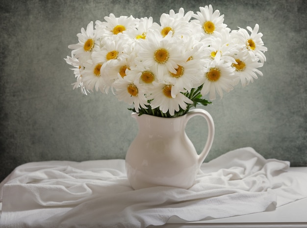 Still life with bouquet of daisy flowers in a jar on wooden table