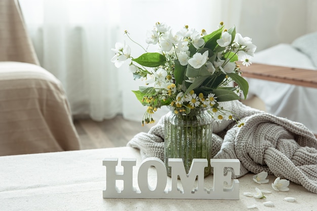 Photo still life with a bouquet of flowers, a book and a wooden decorative word home