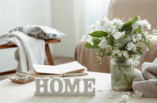 Still life with a bouquet of flowers, a book and a wooden decorative word home.