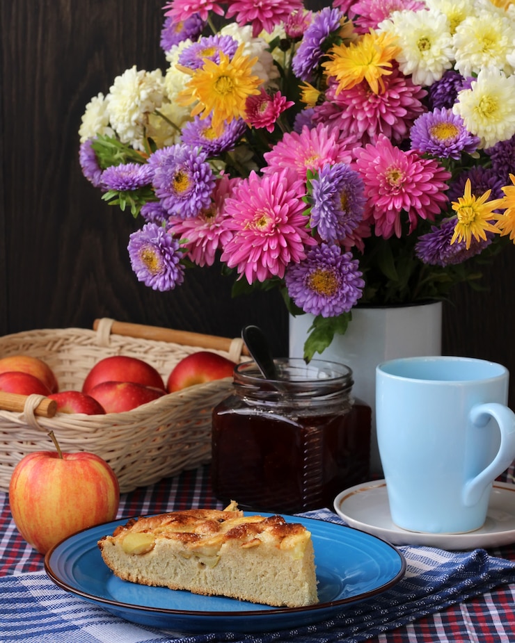 Photo バラの花束と赤いリンゴのケーキのある静物。