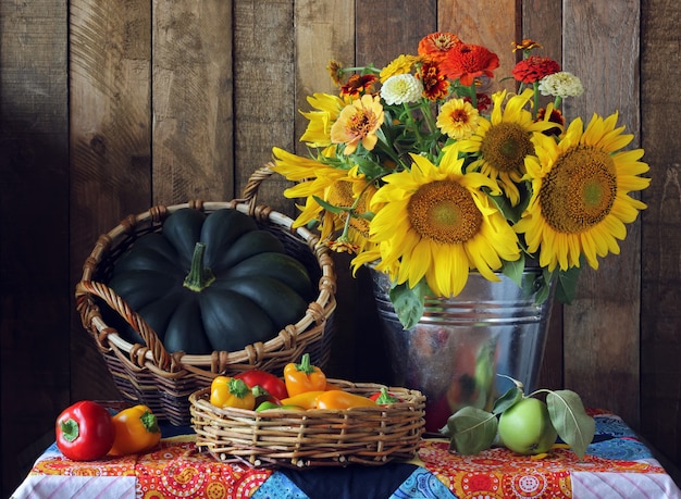 Still life with bouquet of sunflowers, pumpkin, apples and peppers in the basket,