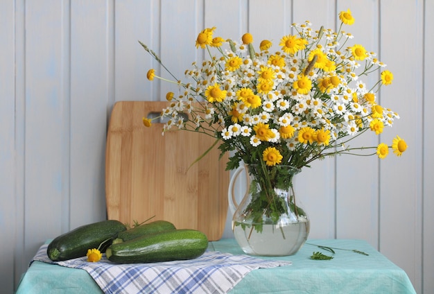 Foto vita morta con un bouquet di margherite gialle e bianche in una brocca e zucca