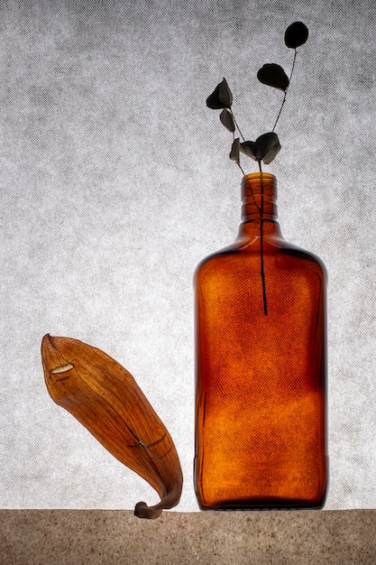 Still life with a brown bottle and a dry leaf