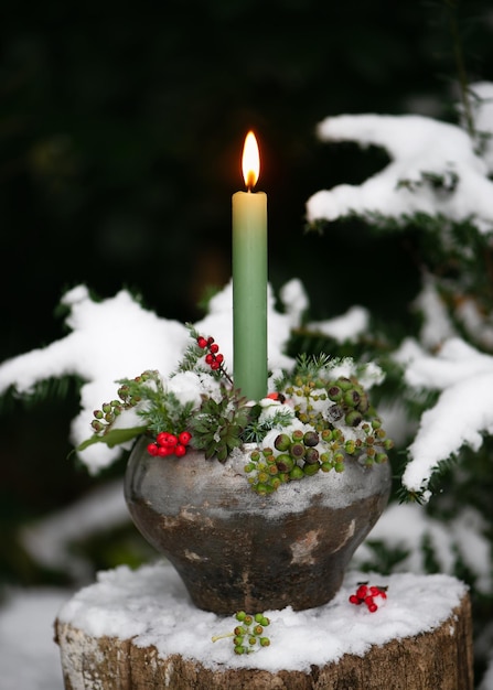 Still life with burning green candle in candle in rustic metal pot Outdoor Christmas decor