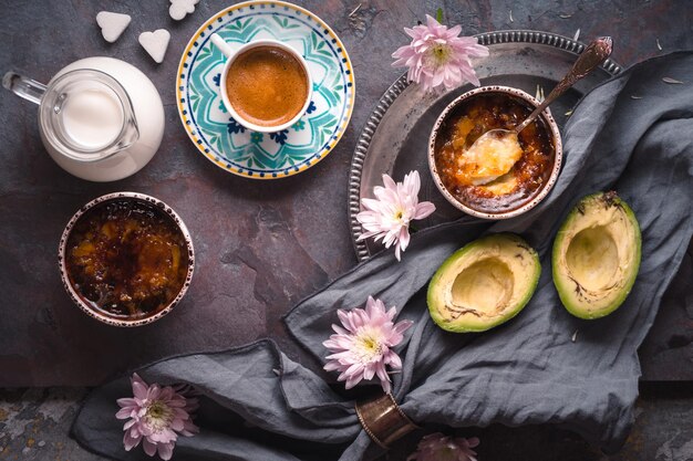 Still life with Catalan cream avocado and cup of coffee on the stone background top view