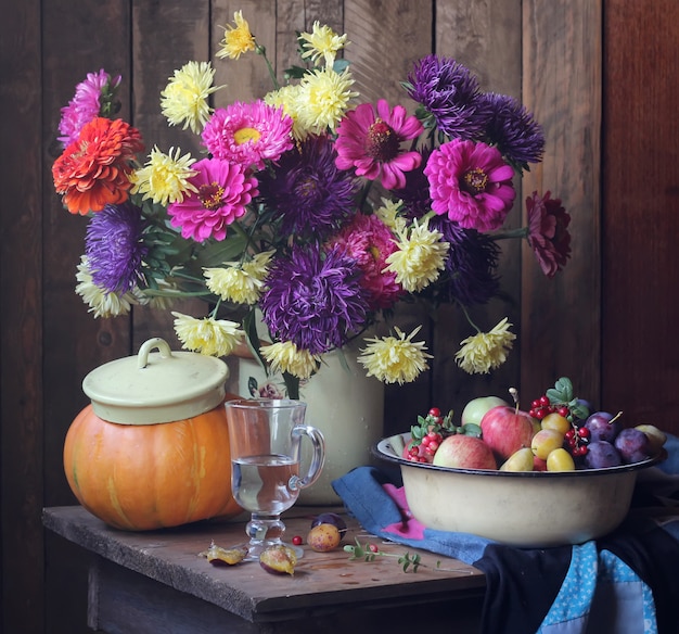 Still life with chrysanthemums and asters, plums, apples and cranberries in the dish 