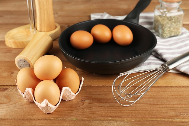 Still life with eggs and pan on wooden background