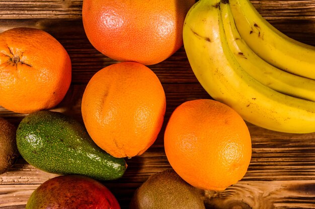 Still life with exotic fruits. Bananas, mango, oranges, avocado, grapefruit and kiwi fruits on rustic wooden table. Top view