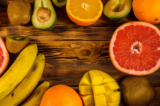 Still life with exotic fruits Bananas mango oranges avocado grapefruit and kiwi fruits on rustic wooden table Top view