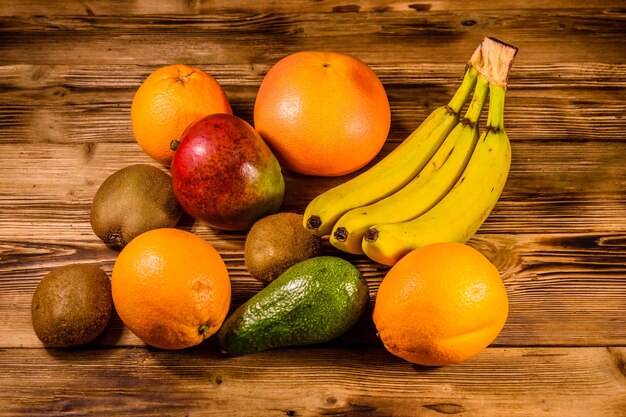 Still life with exotic fruits. Bananas, mango, oranges, avocado, grapefruit and kiwi fruits on rustic wooden table