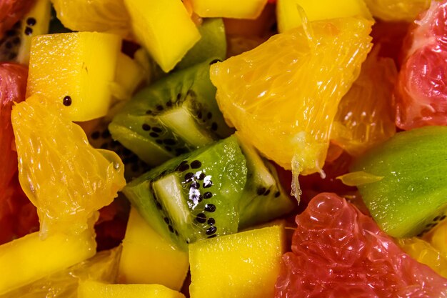 Still life with exotic fruits. Bananas, mango, oranges, grapefruit and kiwi fruits on rustic wooden table