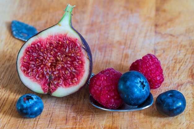 Still life with fresh fig, raspberries and blueberries on the wooden table