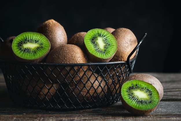 Still life with fresh kiwi fruit in a metal basket on a dark background closeup