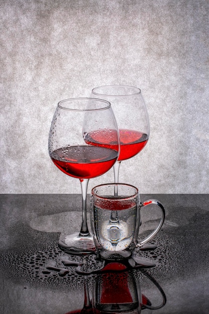 Still life with glasses of liquid on a wet table