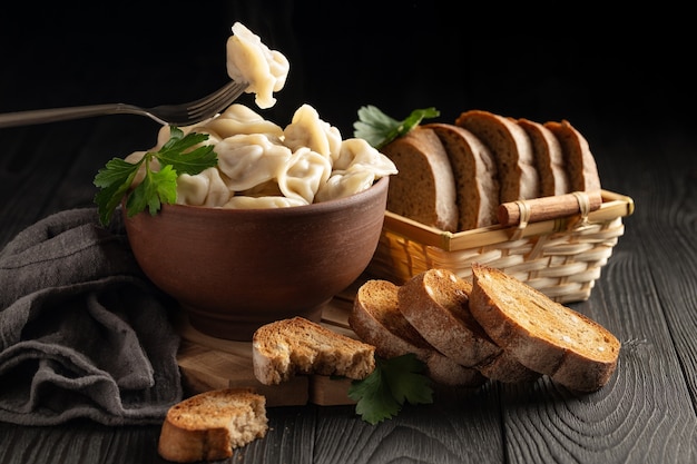 Still life with hot dumplings in a clay bowl and toasted rye bread