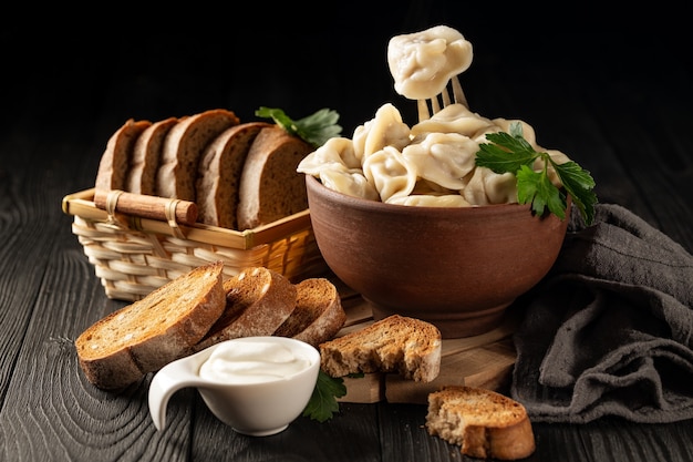 Still life with hot dumplings in a clay bowl and toasted rye bread