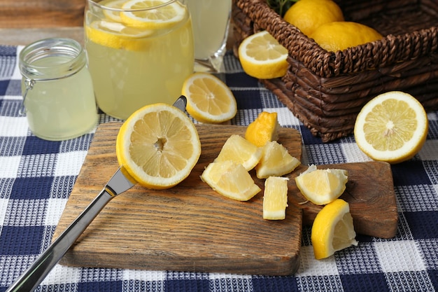 Photo still life with lemon juice and sliced lemons on wooden cutting board and napkin closeup