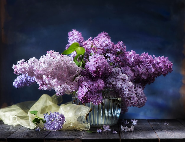 木製の背景に花瓶にライラックの花と静物