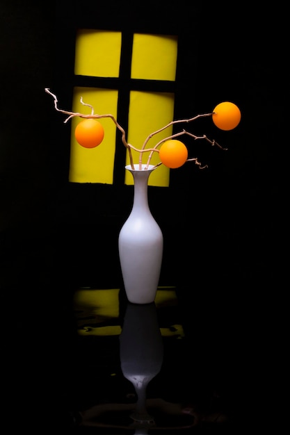 写真 窓の背景にある白い花瓶の中のオレンジ色のボールの静物
