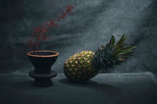 パイナップルと枝のある茶色の花瓶のある静物