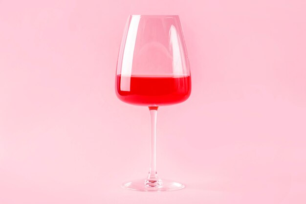 Still life with red refreshing summer alcoholic cocktail drink with strawberry in wine glass isolated on pink background