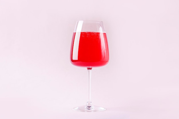 Still life with red refreshing summer alcoholic cocktail drink with strawberry in wine glass isolatedon pink background