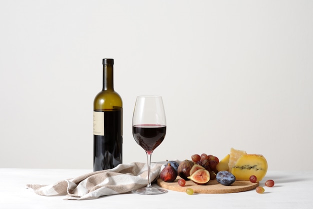 Still life with red wine, cheese and fruits background