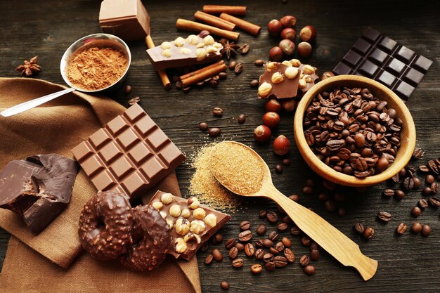 Still life with set of chocolate nuts and spices on wooden table closeup