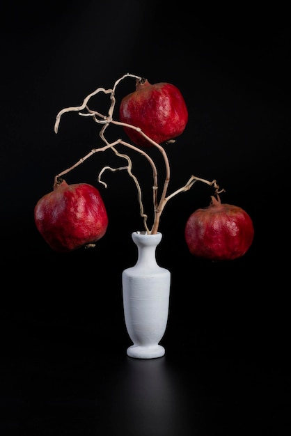 Still life with three pomegranates on branches