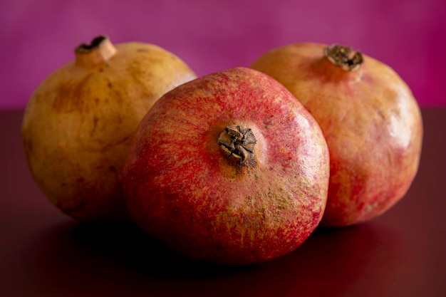 Still life with three red fruit pomegranates on dark table