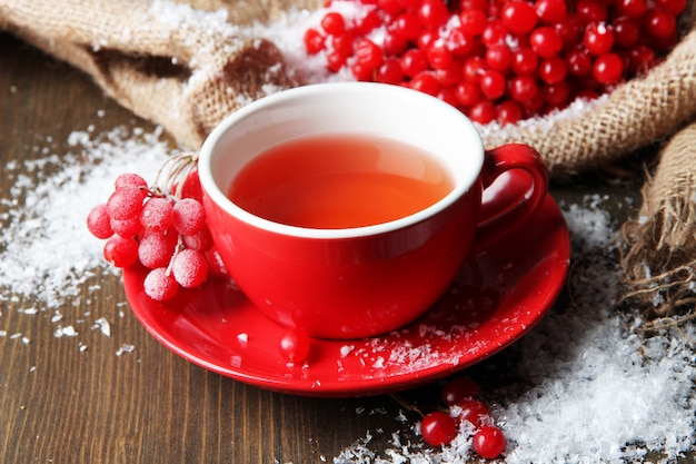 Still life with viburnum  tea in cup, berries and snow, on sackcloth napkin