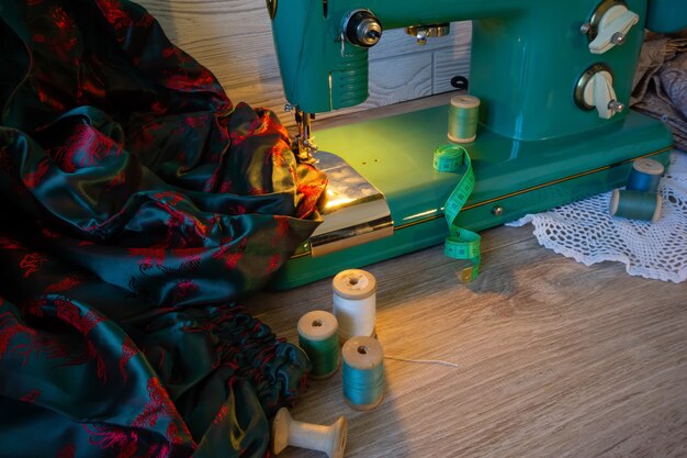 Still life with vintage electric sewing machine, fabrics and spools of thread