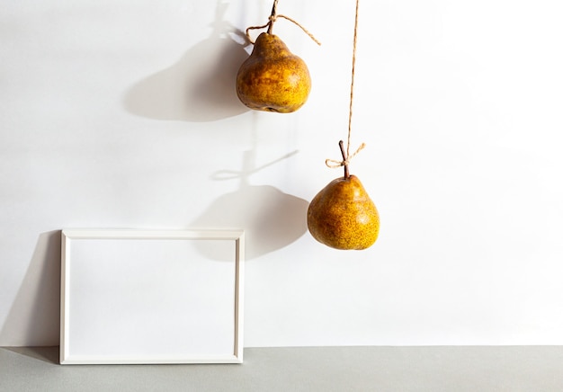 Still life with white blank photo frame and pears