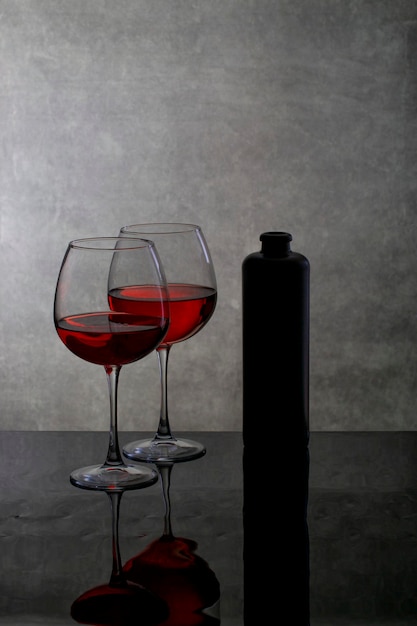 Still life with wine glasses and a bottle on a reflective surface