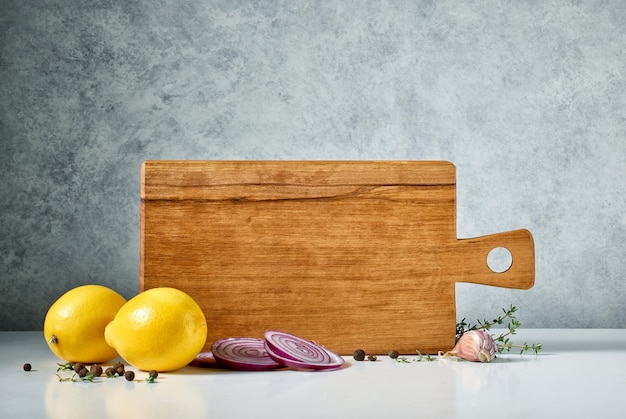 Photo still life with wooden cutting board and spices on grey background