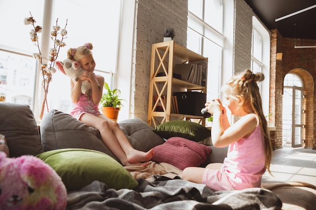 Stille kleine meisjes spelen in een slaapkamer in schattige pyjama's, huiselijke stijl en comfort