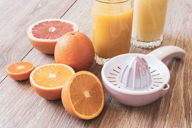 Stilleven diverse hele en gesneden citrusvruchten handmatige ruimer en glas sinaasappelsap