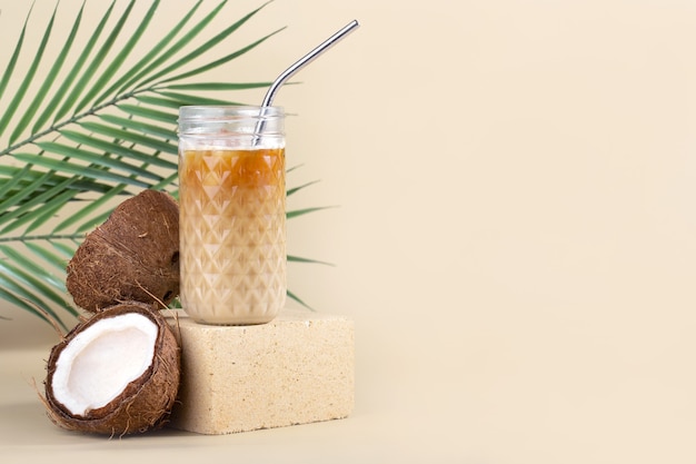 stilleven iced americano met kokosmelk in een longdrink en een metalen buis op een steen