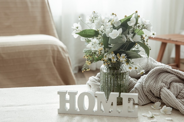 Stilleven met een boeket bloemen, een boek en een houten decoratief woordhuis.