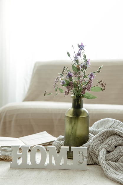 Stilleven met een boeket bloemen, een boek en een houten decoratief woordhuis.