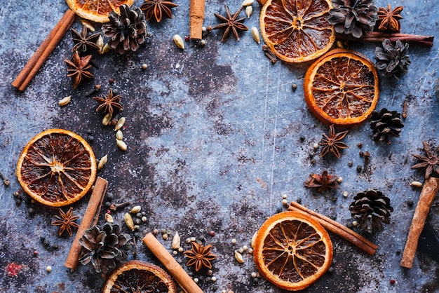 Stilleven met een set glühwein. gedroogde sinaasappel, kaneelstokjes, roze peper, kardemom, anijs, kruidnagel op een blauwe achtergrond.