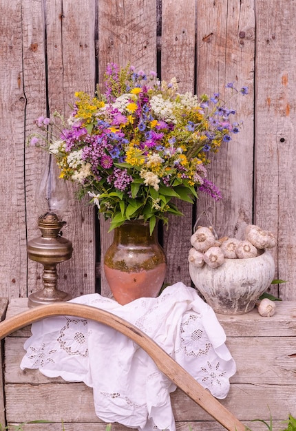 Stilleven met een veelkleurig boeket van wilde bloemen in een kruik op een houten ondergrond in rustieke stijl