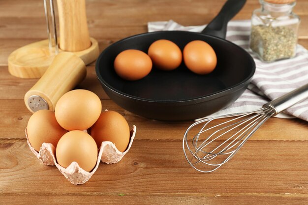 Stilleven met eieren en pan op houten achtergrond