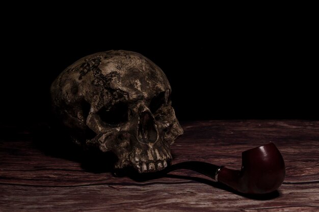 Stilleven met menselijke schedel oude tabakspijp op houten tafel