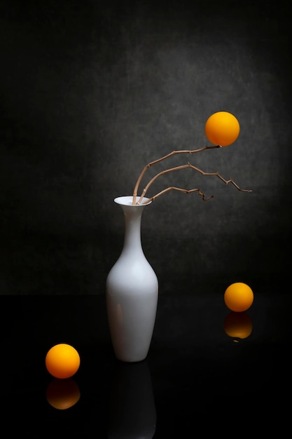 Stilleven met oranje bollen in een witte vaas