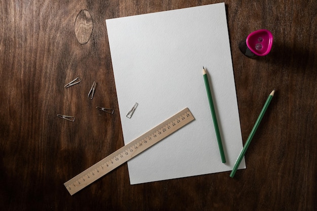 Stilleven met potloden stuk papier en puntenslijper op een donkerbruine tafel met houtstructuur